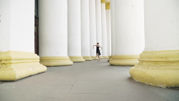 Extreme Wide Shot of Graceful Slim Young Ballerina Dancing on Tiptoes Between Enormous White Columns