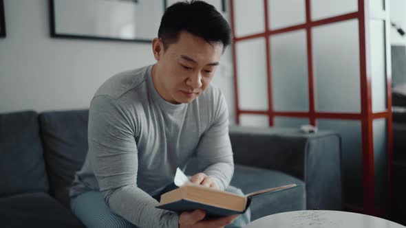 Concentrated Asian man reading book