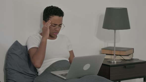 African Woman Having Headache While Working on Laptop in Bed