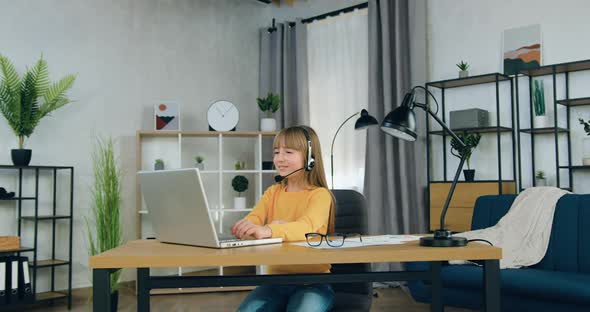 Girl in Headphones Sitting in front of Laptop and Talking with Teacher During Video Meeting