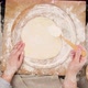 Female hand sprinkles rolled out yeast pizza dough with white wheat flour - VideoHive Item for Sale
