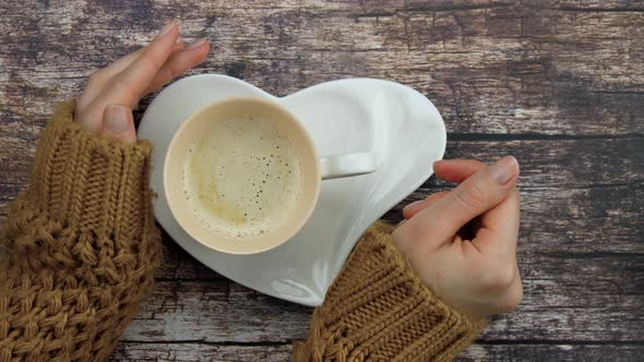 Hands of a Girl in a Knitted Jacket Hugging a Bowl of Coffee or Cappuccino