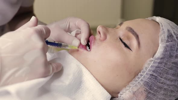 Closeup View of Beautician Hands Doing Injection in Woman Lips