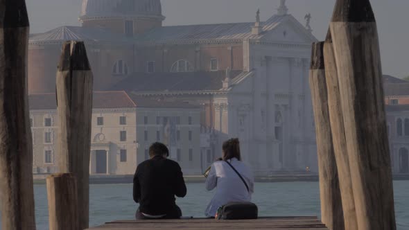 Couple Sitting on the Pier and Drinking Alcohol. Venice, Italy