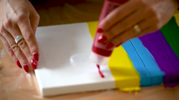 A woman painting colorful stripes on a canvas