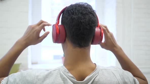 African Man Wearing Headphones for Listening Back View