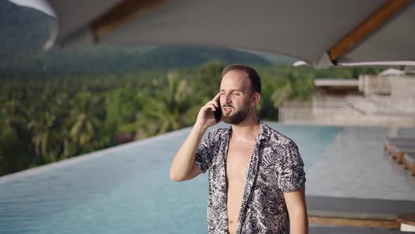 Outdoors Shot of a Hipster Young Man with a Beard Talking on the Mobile Phone While Standing on a