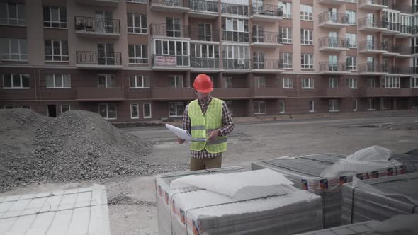 Male Builder Considers Brought Building Material at Construction Site Controls Materials