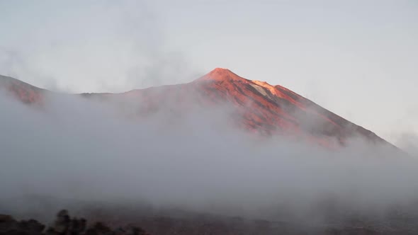 El Teide volcano during sunset behind the low clouds. View from car window. Canary islands, Spain.