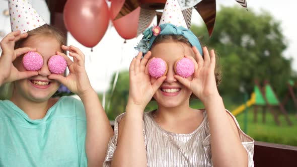 The Birthday Girl and Her Friend Have Fun at a Birthday Party. The Girls Are Holding Pink Cookies