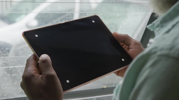 Video of african american senior man using tablet with black screen