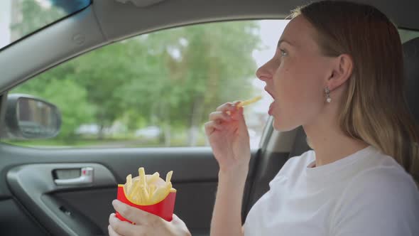 Female Eating Fries in the Car. Hands Holding a Paper Bag with Fast Food Fried Potatoes.