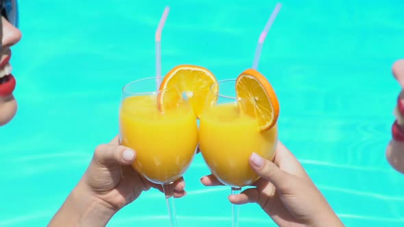 Two Slim Attractive Women Clinking Cocktail Glasses in Swimming Pool, Party