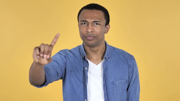 Young African Man Waving Finger to Refuse Yellow Background