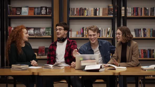 Group of Young Students Talking Using Laptop Explaining Course Work Study Together in Library