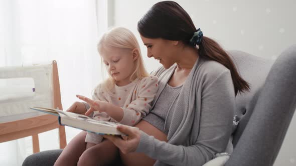 Caucasian woman in advanced pregnancy reading book with her elementary daughter. Shot with RED heliu