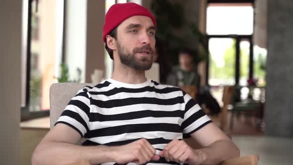 Modern guy wears a beard, actively gestures with his hands