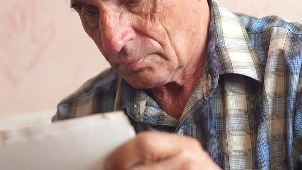  portrait of a caucasian pensioner 70-79 years old looking through photos holding in his hands.selec