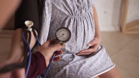 Pregnant Woman's a Doctor Examines the Woman and Measures Her Blood Pressure