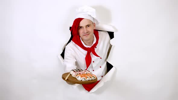 Young Man Dressed As Chef Holding Wooden Board with Sushi Rolls