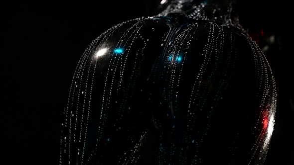 Closeup of a Swaying Female Ass in a Black Latex Suit and Streaked with White Liquid on a Dark