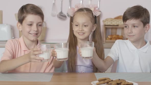 Three Happy Caucasian Children Clinking Glasses with Milk and Drinking Tasty Dairy Product, Portrait