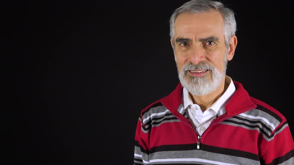 An Elderly Man Presents Something To the Camera with a Smile - Black Screen Studio