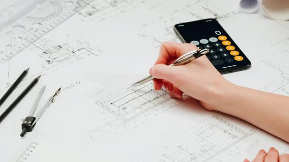 Architect Designer Counting on a Calculator Drawing Plan Blueprint Closeup
