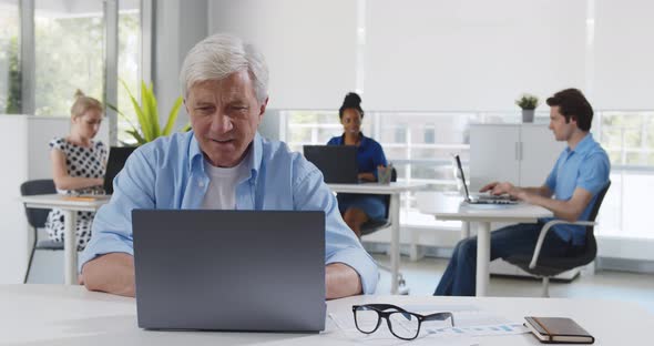 Mature Businessman Analyzing Data on Laptop in Creative Open Space Office