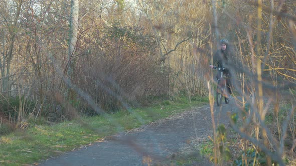 Man cycling through forest path during golden hour. RACK FOCUS 4K