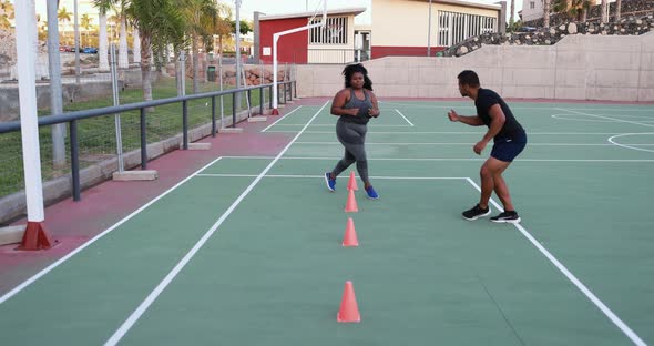 Curvy woman doing running exercise with her personal trainer outdoor 