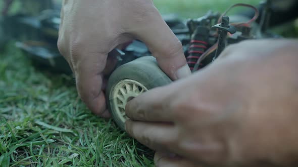 Changing the dusty tires of a remote controlled car with a screwdriver while the whole hood is open