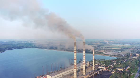 Aerial view of coal power plant high pipes with black smokestack polluting atmosphere.