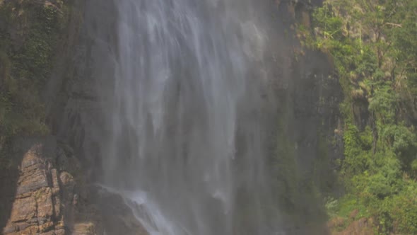 Waterfall at Rocky Cliff with Green Trees and Grass Slow