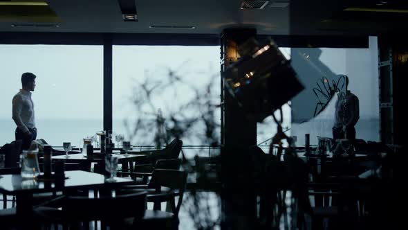 Handsome Man Silhouette Spending Time in Classic Dark Cafe Guest Hall Interior