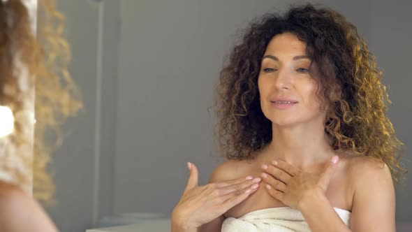 Beautiful Mature Woman Applies a Cosmetic Serum to the Skin of the Neck and Decollete