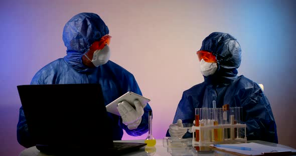 Two Chemists Are Conducting Experiments in Laboratory, People Are Wearing Hazmat, Face Masks and