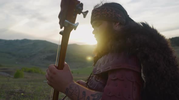 Plump Musician Plays Igil with Bow Against Mountain at Dawn