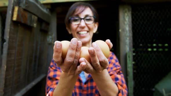 Mature woman holding brown eggs in the pen