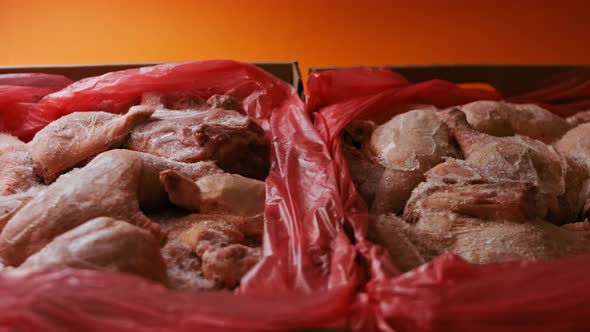 Closeup View of Hands in Gloves Packing Chicken Legs From a Box Into Individual Plastic Bags