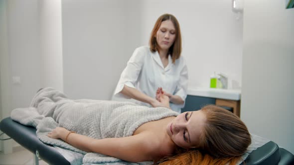 Massage - Masseuse Is Kneading Wrist of a Woman on a Couch