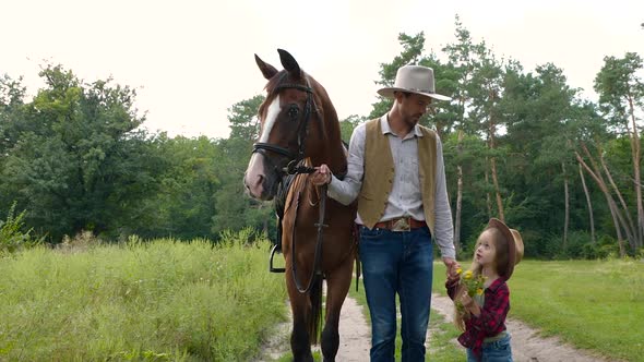Cowboy with His Daughter Walking with a Horse on a Forest Road