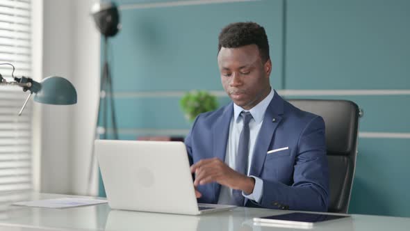 African Businessman Having Wrist Pain While Using Laptop in Office