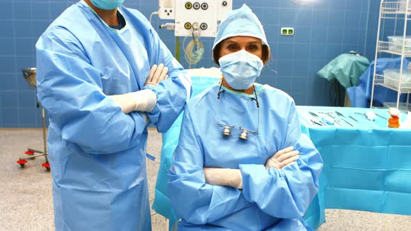 Portrait of male and female surgeons with arms crossed in operation room