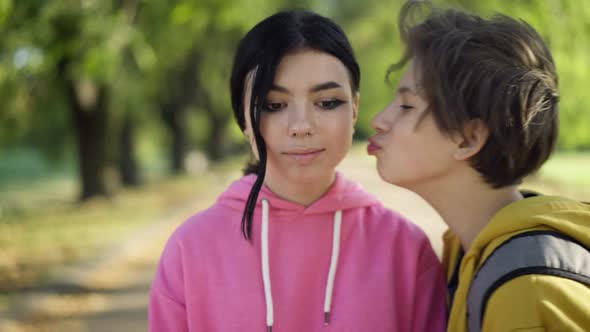 Portrait of Teenage Caucasian Girl Looking at Camera As Boy Appearing Kissing Cheek Posing in