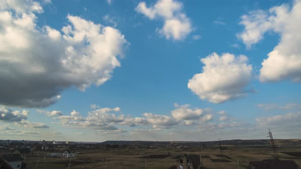 Time lapse footage of fast moving white puffy clouds on blue clear sky.