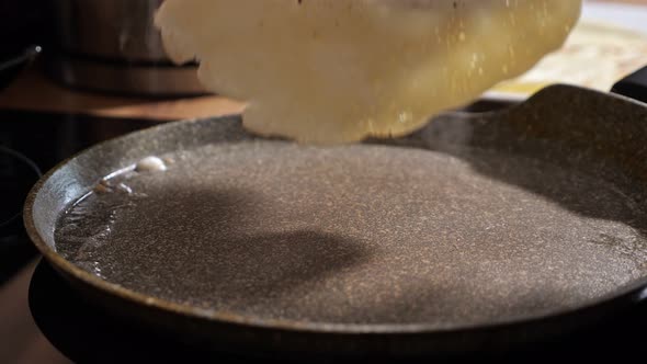 Unrecognizable Woman Turns a Pancake in a Frying Pan with a Spatula Closeup