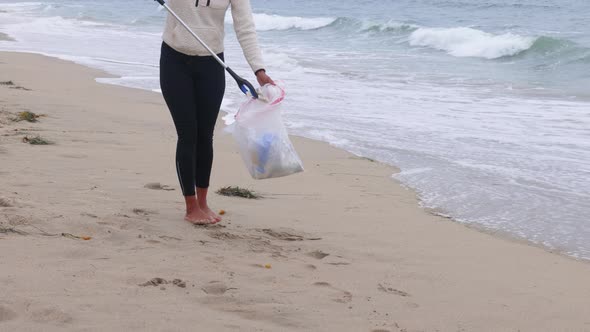 Woman picking up litter from the bech.