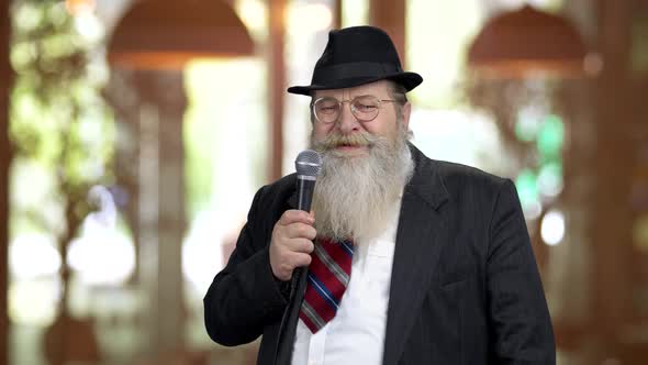 Old Bearded Man in Suit Talking with Microphone
