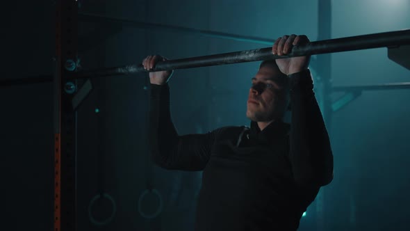 Strong Sporty Man Doing Workout and Pulls Up on Horizontal Bar in Fitness Gym
